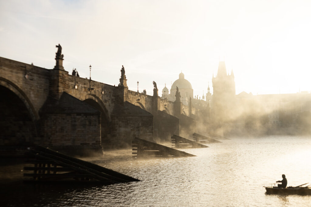 Charles Bridge in Prague at sunrise with mist over the Vltava river